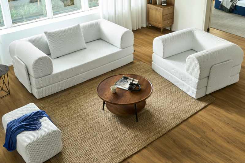 Modern living room with white sofa set and wooden coffee table.