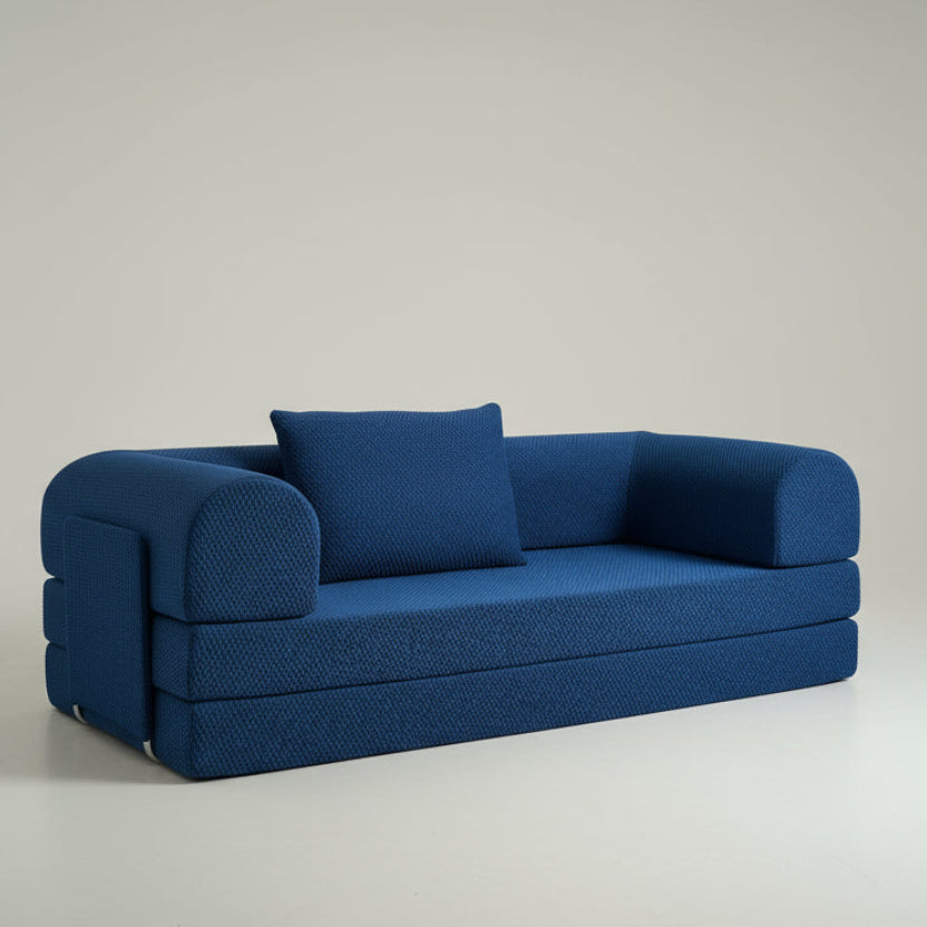 Blue sofa bed on a white floor with a white curtain in the background