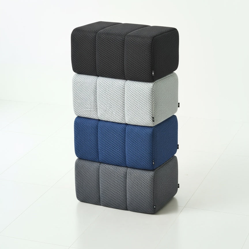 Stack of four Ottoman cubes in black, white, blue, and gray on a white background