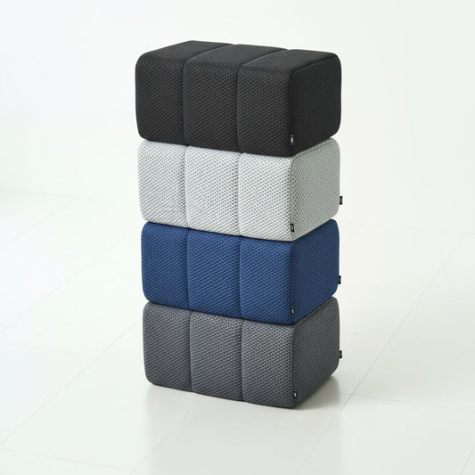 Stack of four Ottoman cubes in black, white, blue, and gray on a white background
