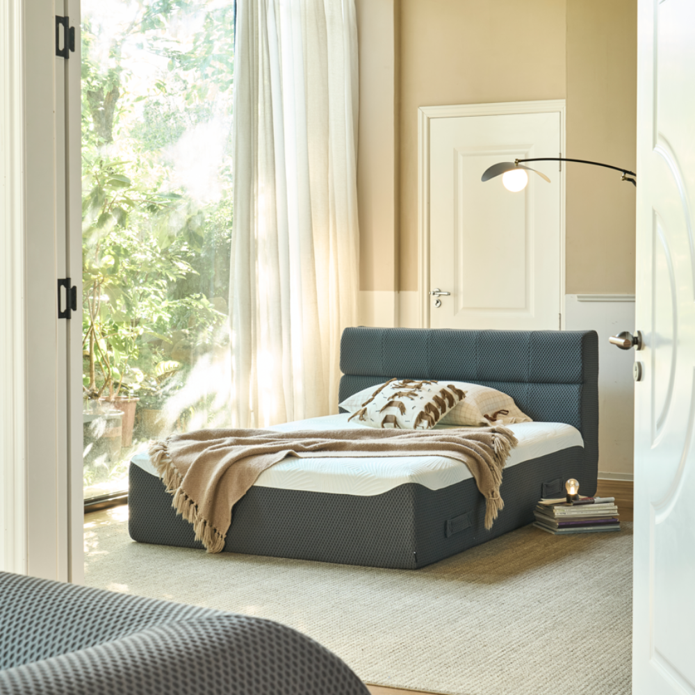 Modern bedroom with a gray upholstered bed and white bedding.