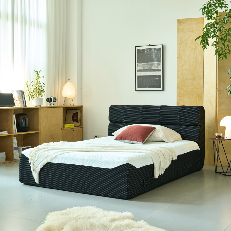 Modern bedroom with a black Queen Size bed, white bedding, and wooden bookshelf.
