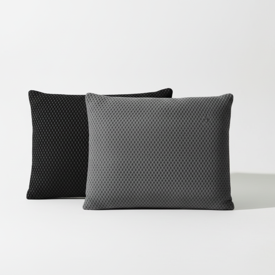 Two textured pillows, one black and one gray, on a light green background.