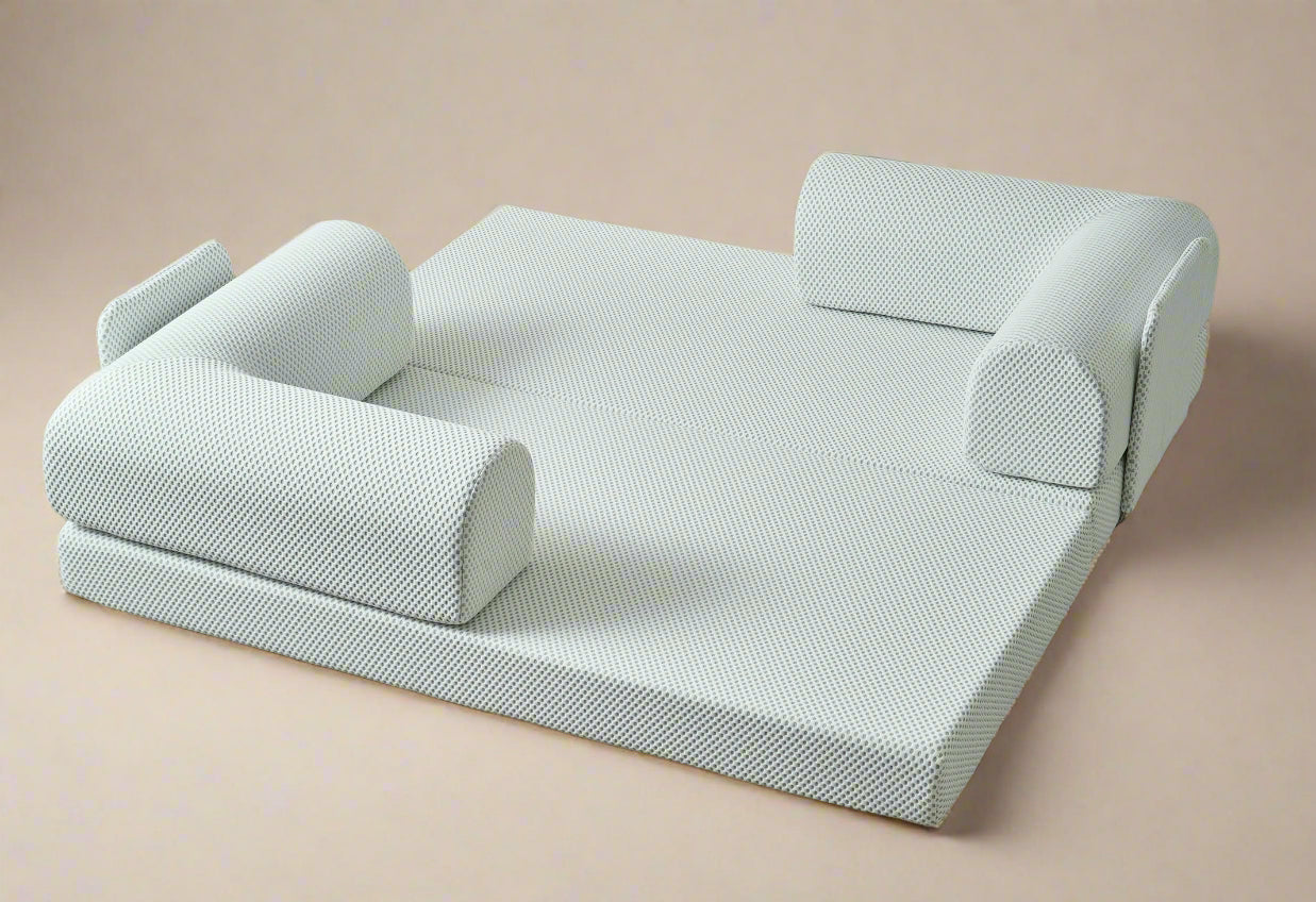 White textured sofa bed in a minimalistic room with light gray floor and white walls.