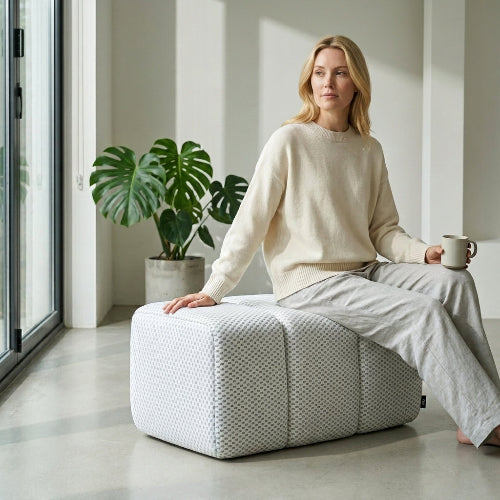 Phaf Toto Ottoman with wooden legs and fabric upholstery, shown in a modern living room setting.